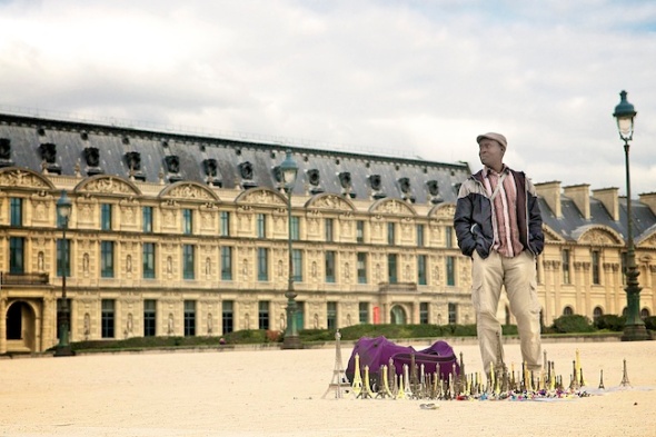 Man sells miniature Eiffel Tower statues in the park at the Louvre, Paris, France.